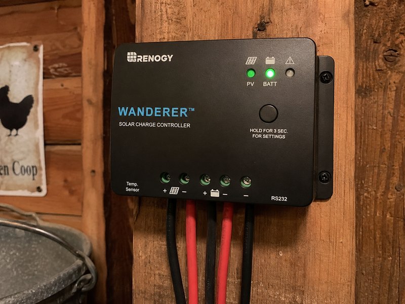 Renogy Wanderer PWM solar charge controller mounted on coop wall with green LED indicators