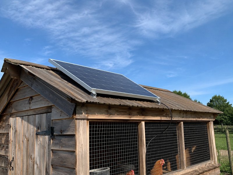 100W monocrystalline solar panel mounted with Z-brackets on a chicken coop roof