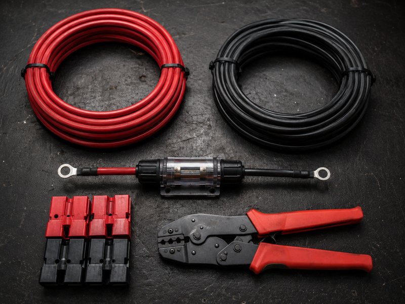 Flat lay of 10 AWG red and black wire, inline fuse holder, Anderson connectors, and crimping tool