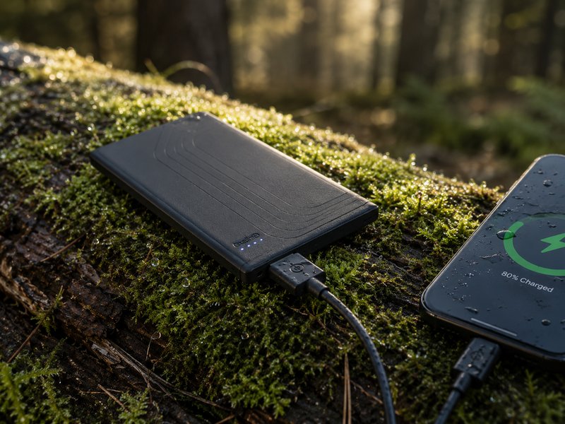 Ultralight power bank on mossy log charging a phone in forest